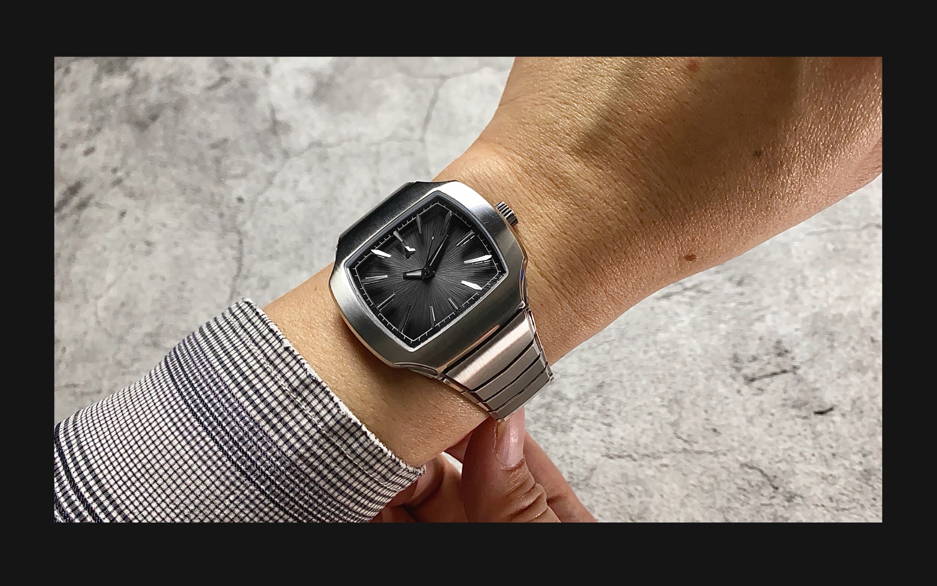 Flux Watch in Vintage Black, worn on the wrist, showcases a black dial with silver markers and a stainless steel bracelet