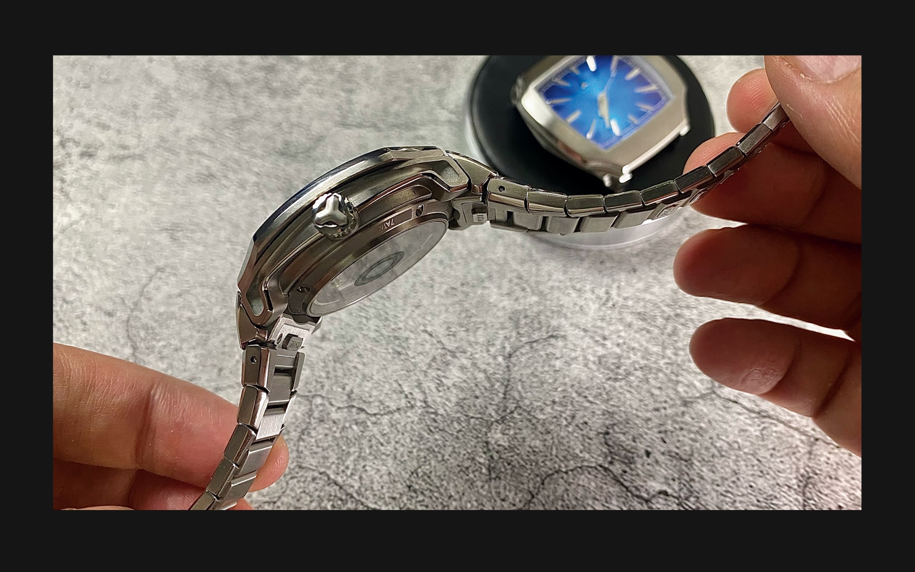 Close-up side view of the Flux Watch, emphasizing the sleek stainless steel bracelet and the prominent crown.