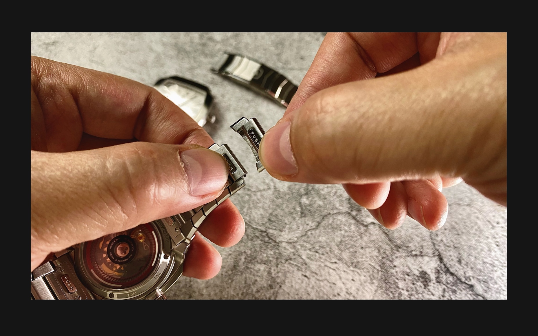 Flux Watch is being resized with hands adjusting the clasp, featuring the stainless steel band and 'Push' system for a secure fit