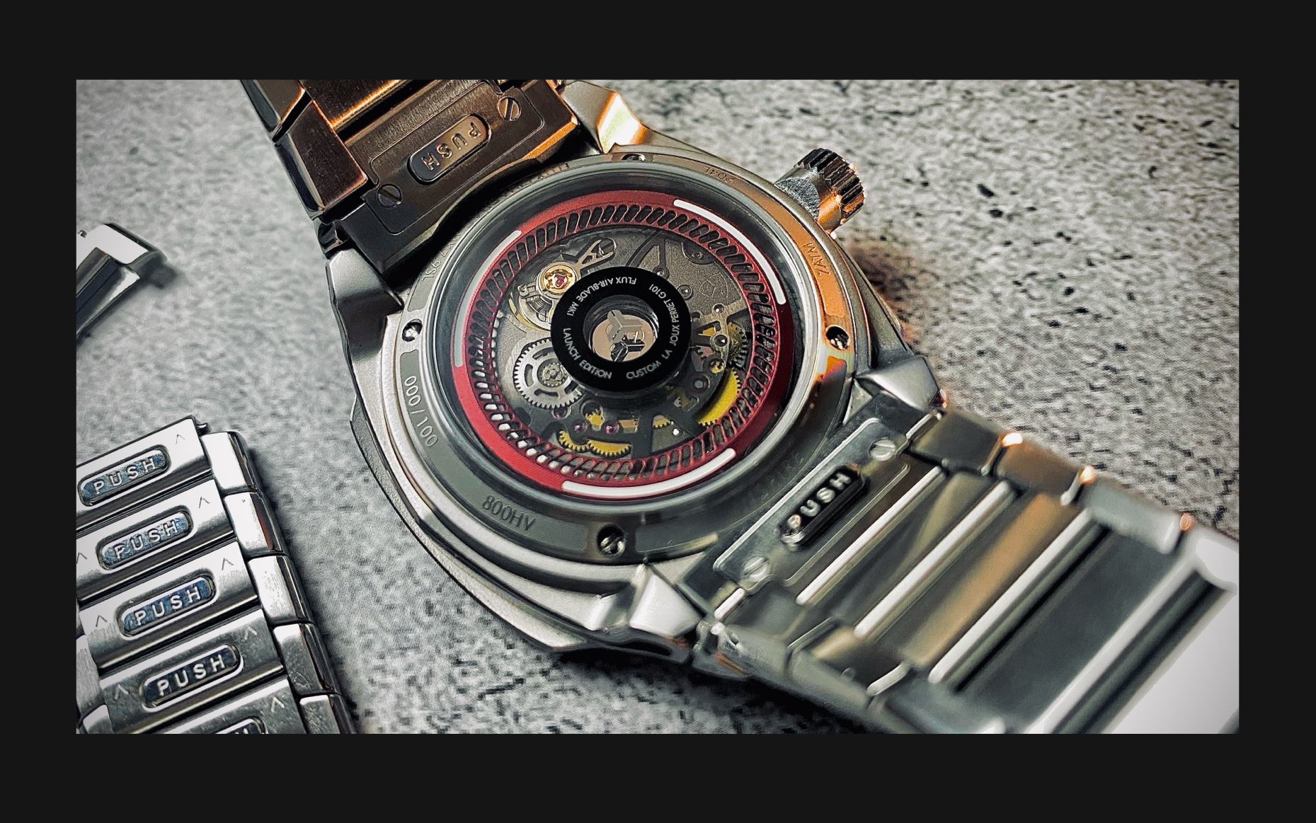Flux Watch back view, featuring the LJP movement with a red rotor, visible gears, and a high-quality stainless steel bracelet